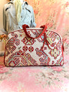 Patterned fabric overnight handbag with red and beige design on a floral background