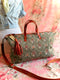 Floral-patterned handbag with brown leather straps on a floral surface
