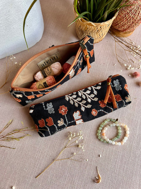 Embroidery floral tool pouch with black background, orange and silver floral patterns, zipper closure, and tan interior, perfect for travel accessories.