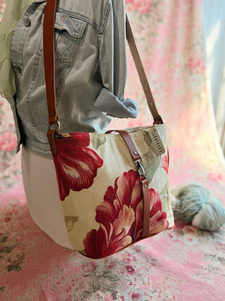 Atenti Crimson Bloom Bella Bucket Bag with large red flowers on pale fabric with a brown strap.