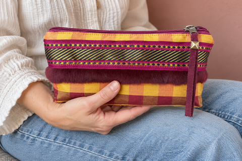 Atenti Cranberry Plaid Tall Tool Pouch held in a seated person's hands, showing its red and gold checks and ribbon trim.