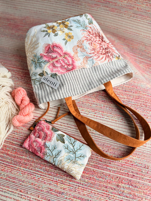 Atenti Primrose Project Tote with pink floral embroidery, striped top trim, brown handles and a matching zipper pouch.